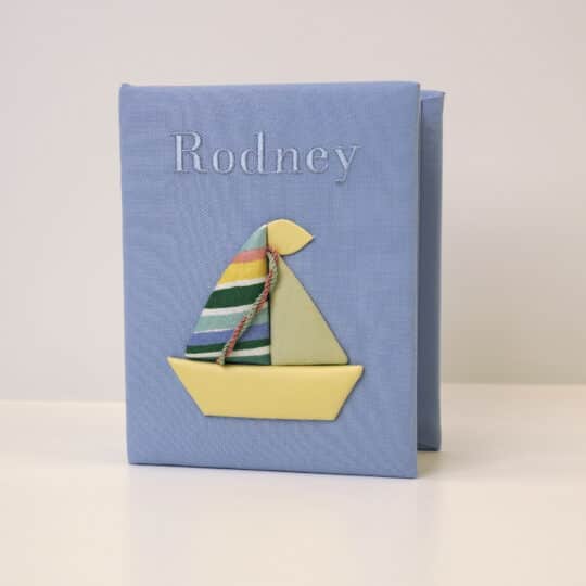 Pima cotton 4x6 baby photo album in cornflower blue with embroidered name 'Rodney' and sailboat applique design.